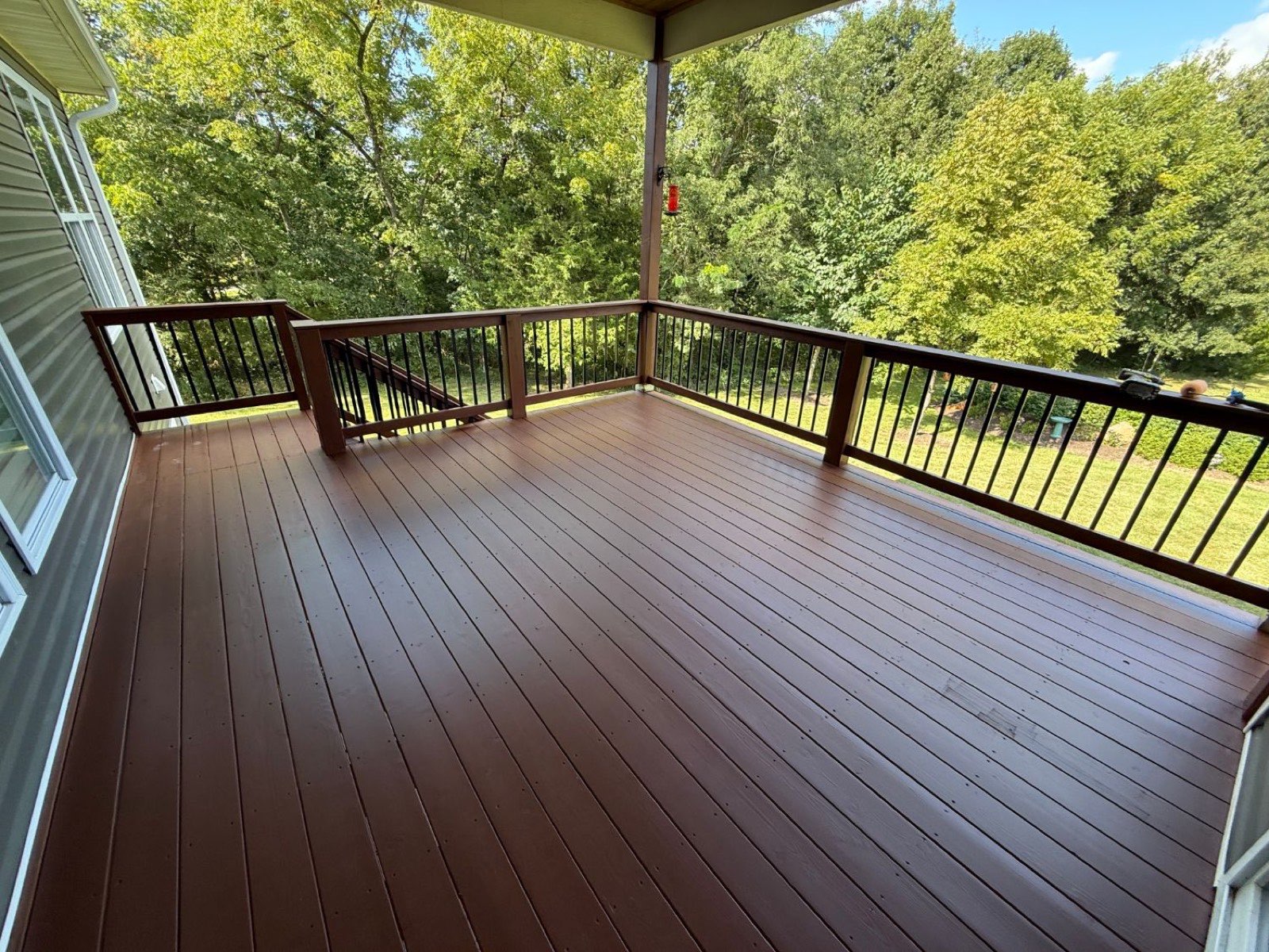 Covered deck floor restained in rich russet brown overlooking a green backyard
