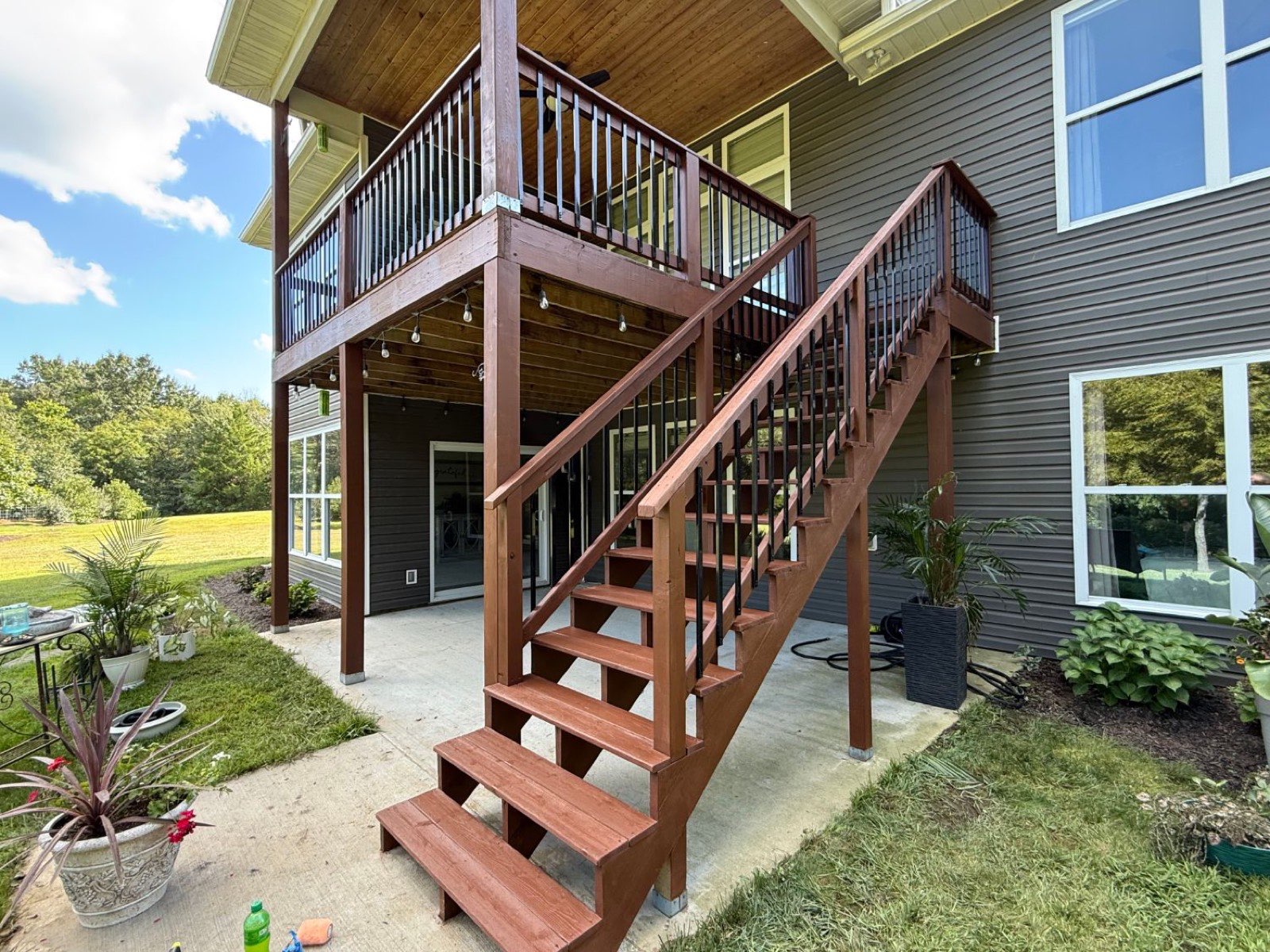 Freshly restained deck staircase with black balusters leading to an upper deck