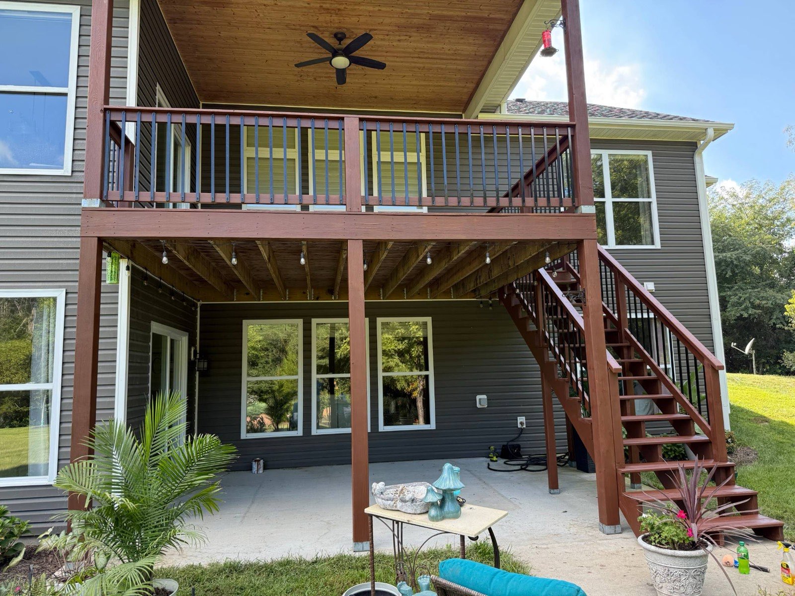 Two-story deck and stairs restained in redwood tones on a gray-sided home