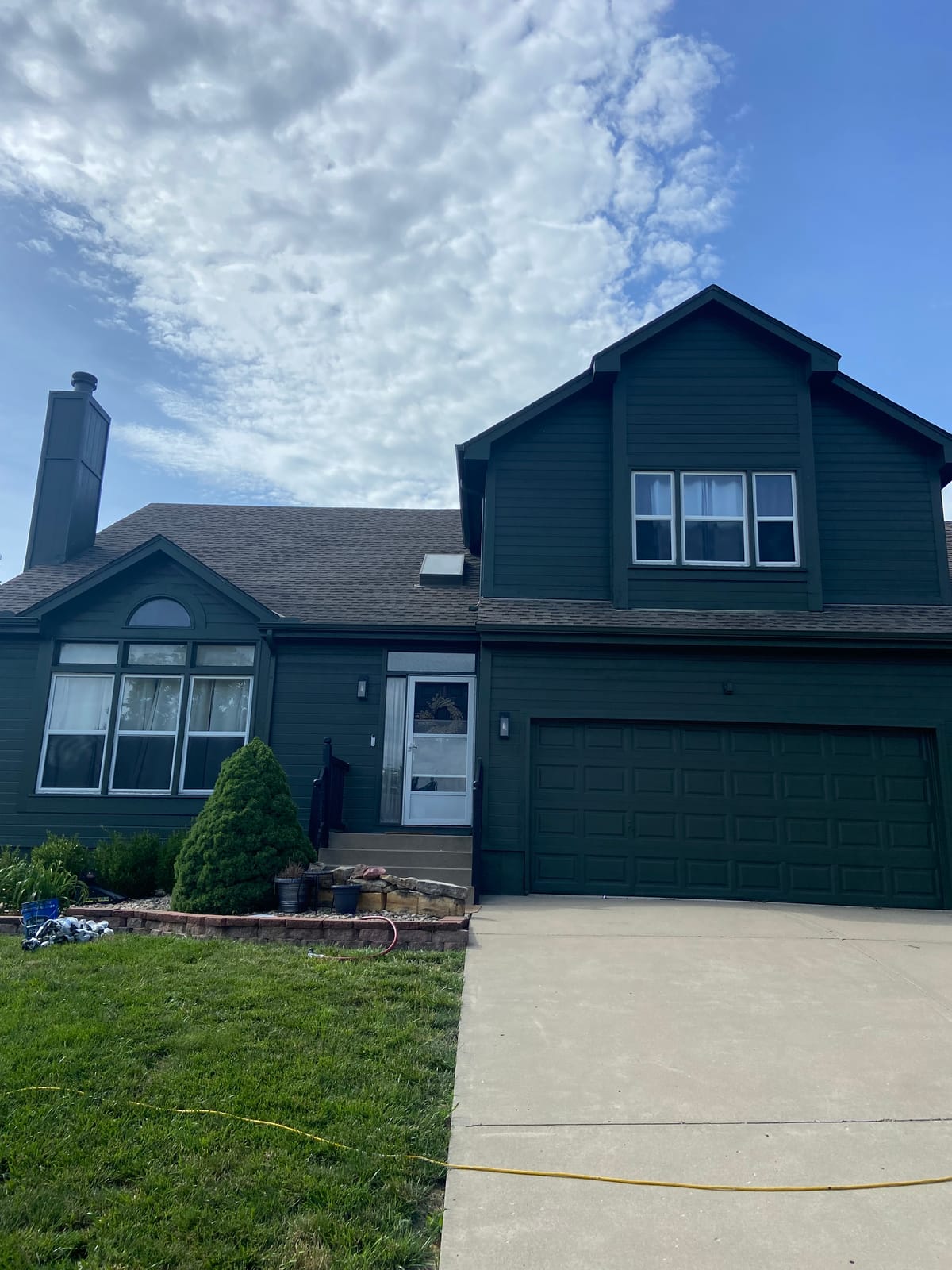 Dark green two-story home with brick after an exterior repaint