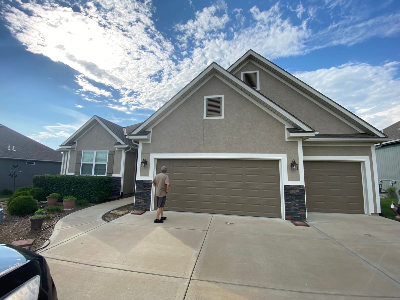Gray stucco home with stone accents and brown garage doors after exterior painting