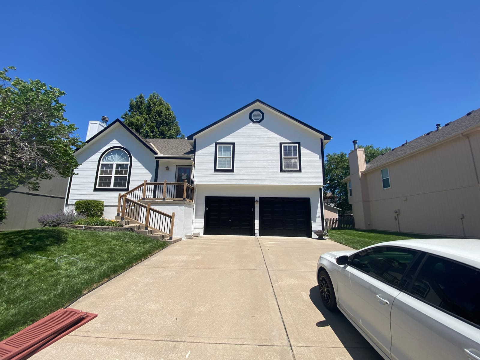 White two-story home with black trim and black garage doors after exterior painting