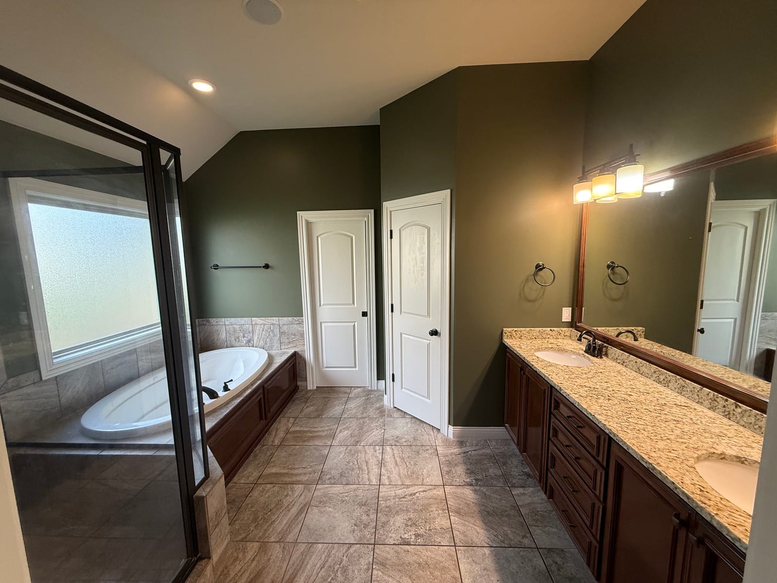 Master bathroom with sage green walls, a granite vanity, and a tiled tub surround