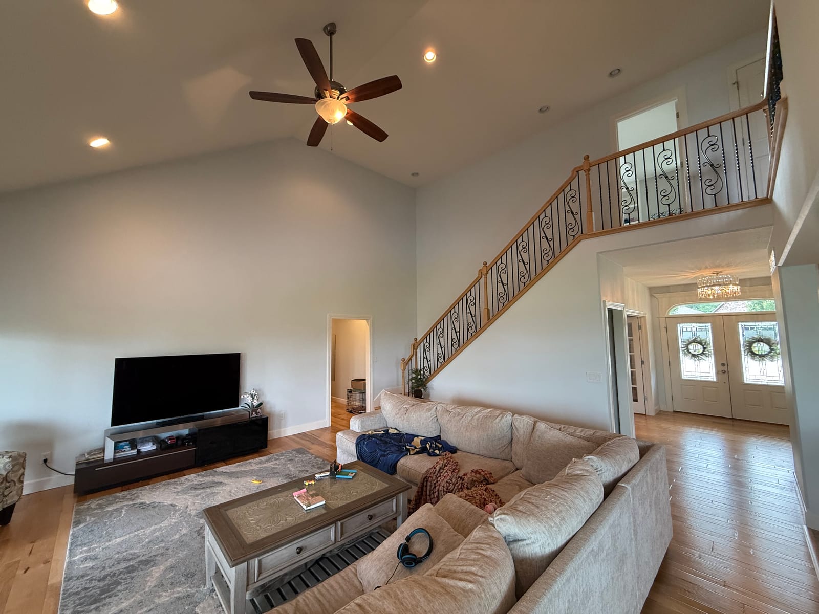 Two-story great room with a staircase, iron railings, and a bright foyer after interior painting
