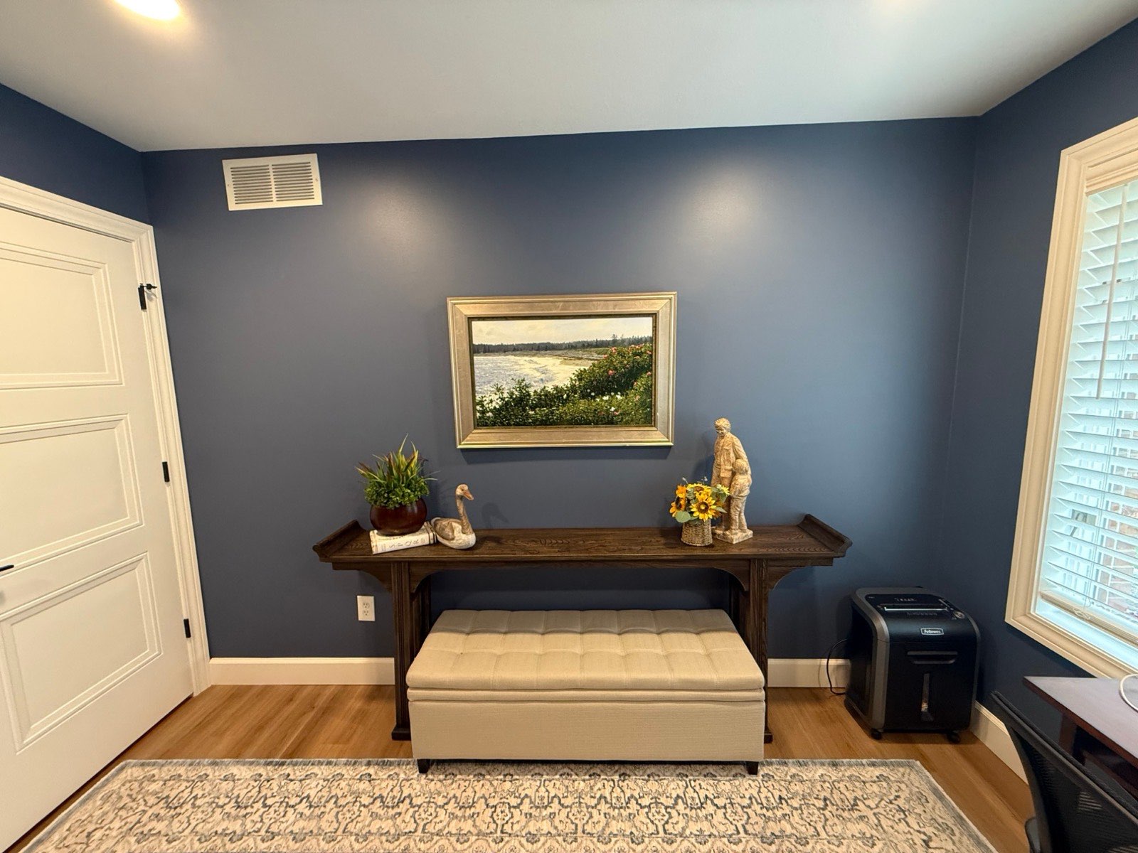 Navy blue office wall with crisp white door and baseboards, console table and artwork