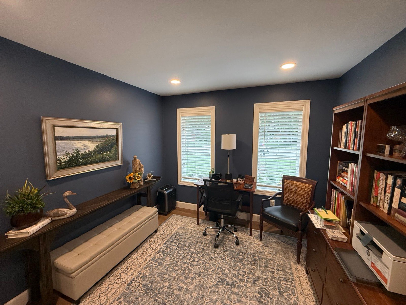Home office painted deep navy blue with white trim, a desk, and built-in bookshelves