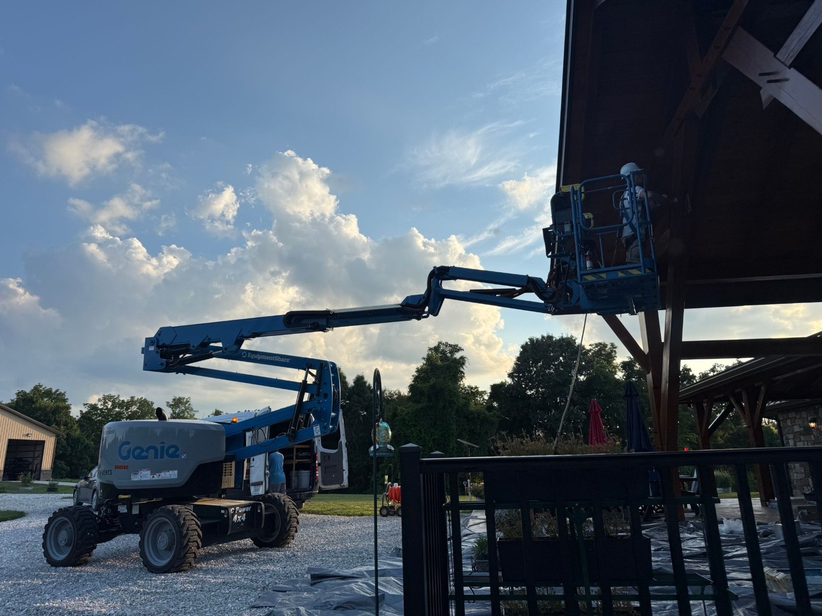 Crew member on a boom lift staining the high gable of a timber pavilion